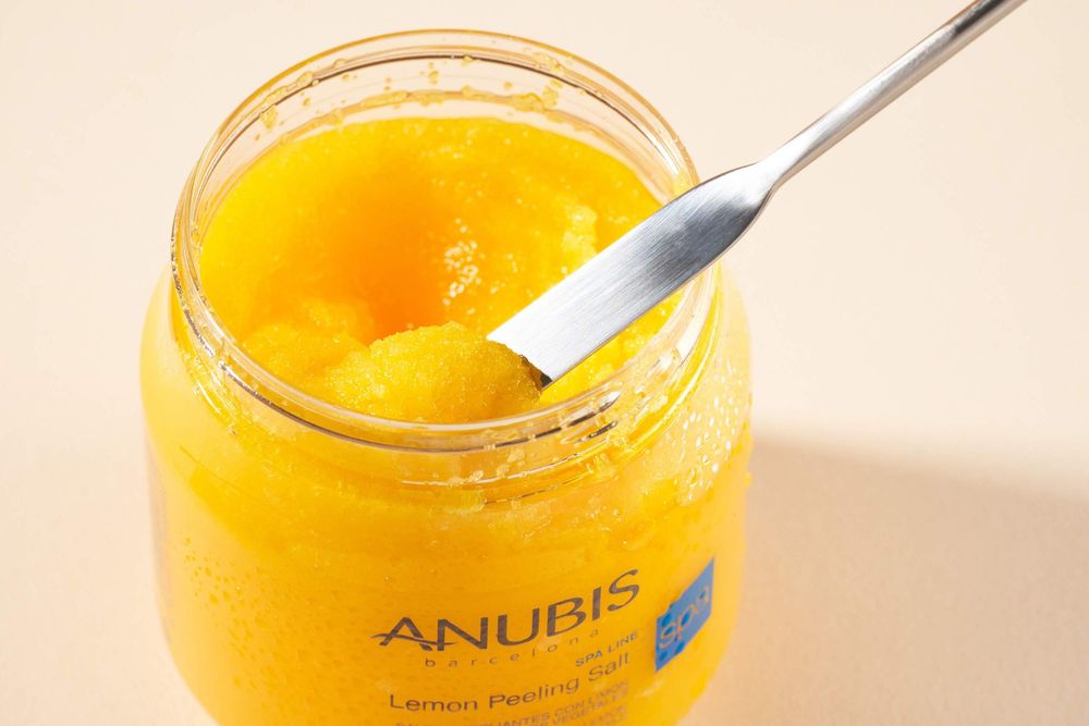 A series of glass jars containing bright yellow honey or golden syrup being scooped with spoons.