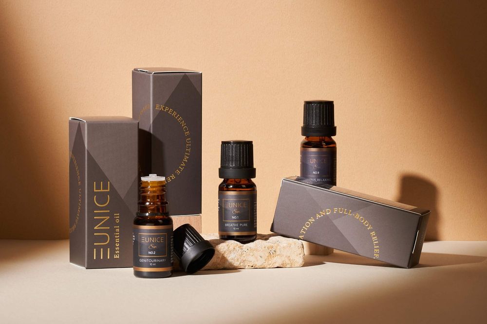 Luxury skincare and essential oil products arranged with dark packaging against a warm brown background.
