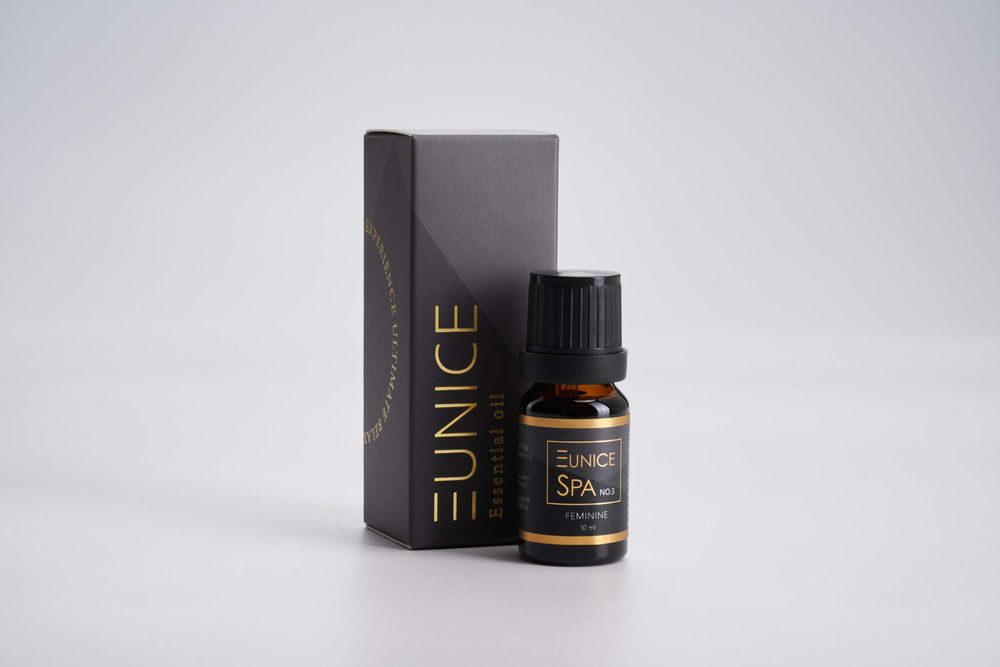 Elegant black glass essential oil bottle with dropper and minimalist packaging on white surface.