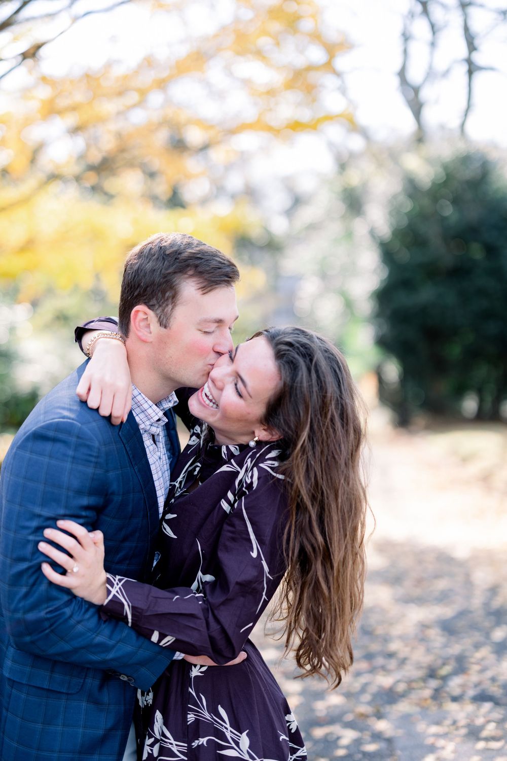 Intimate moment between couple laughing and embracing during fall photoshoot.