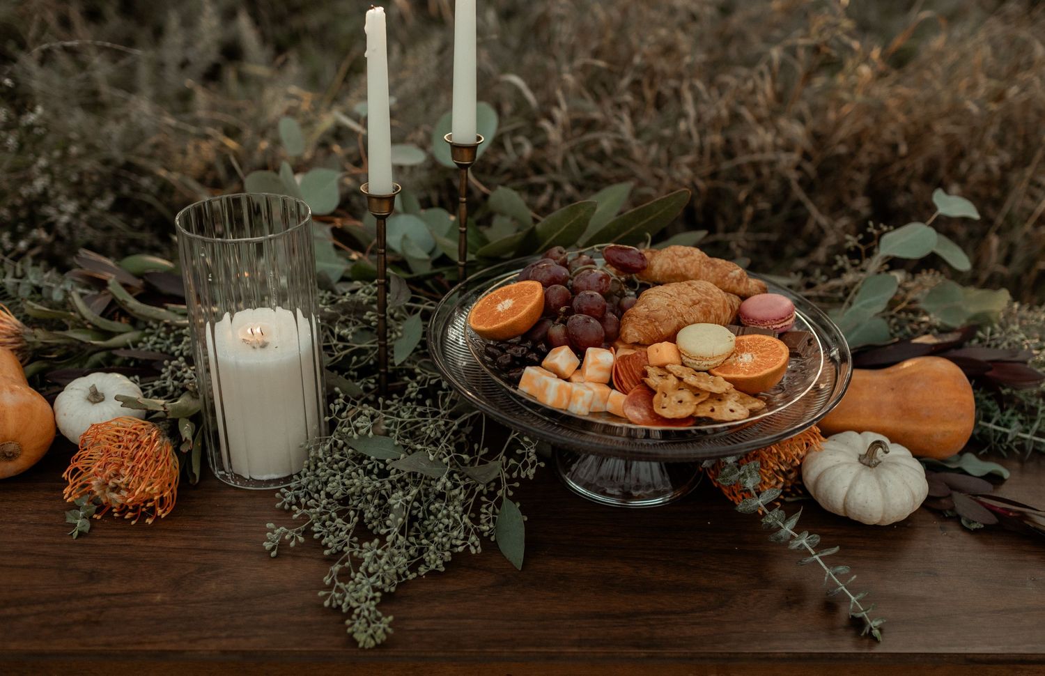 Moody fall table setting with candles, pumpkins, and seasonal decorations.