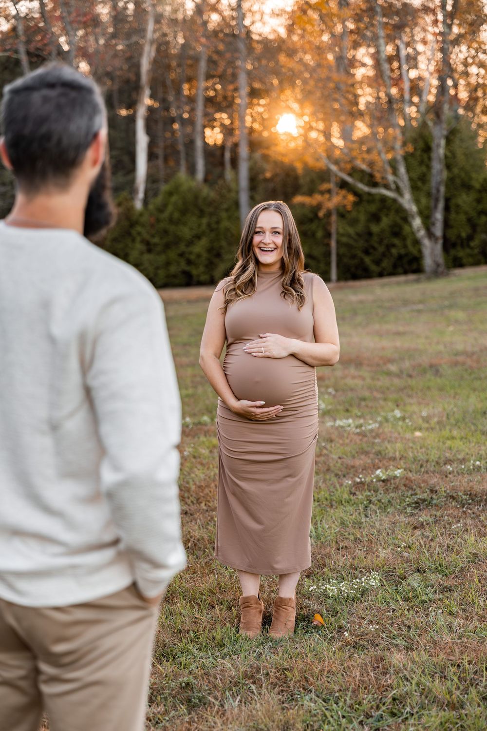 A couple shares a tender moment during an autumn sunset photoshoot in a field with birch trees in the background.
