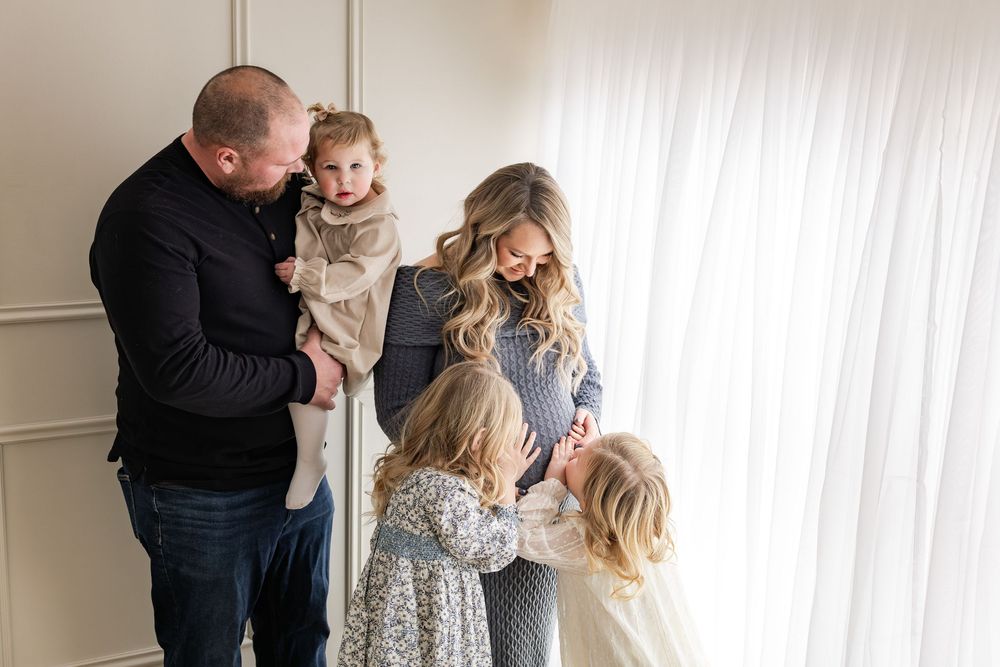 Candid family moments captured against a bright white backdrop in an indoor studio setting.