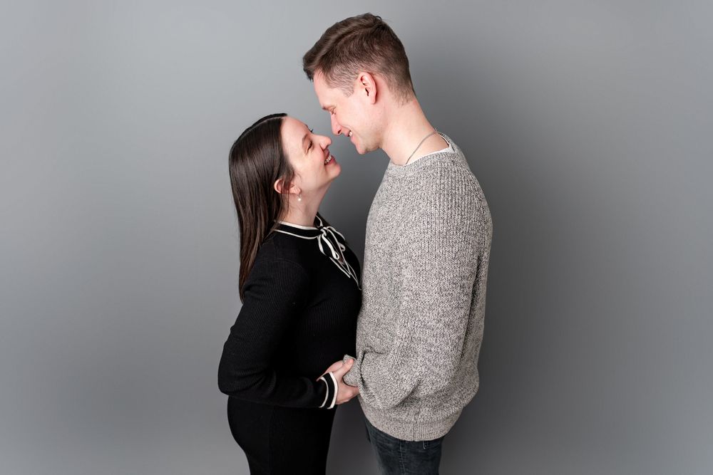 A romantic couple in black and grey clothing share tender moments in a series of intimate black and white portraits.