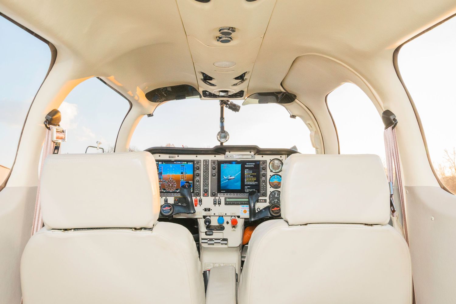 Clean white interior of private aircraft cabin with leather seats and wood paneling.