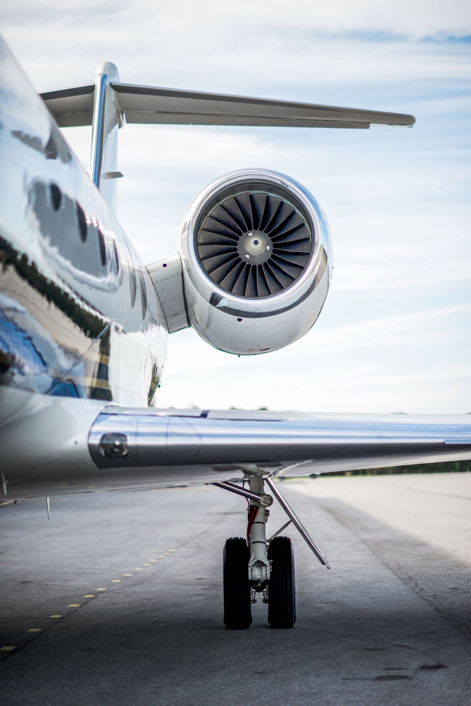 Close-up views of a private jet's turbine engine and landing gear from different angles on an airport tarmac.