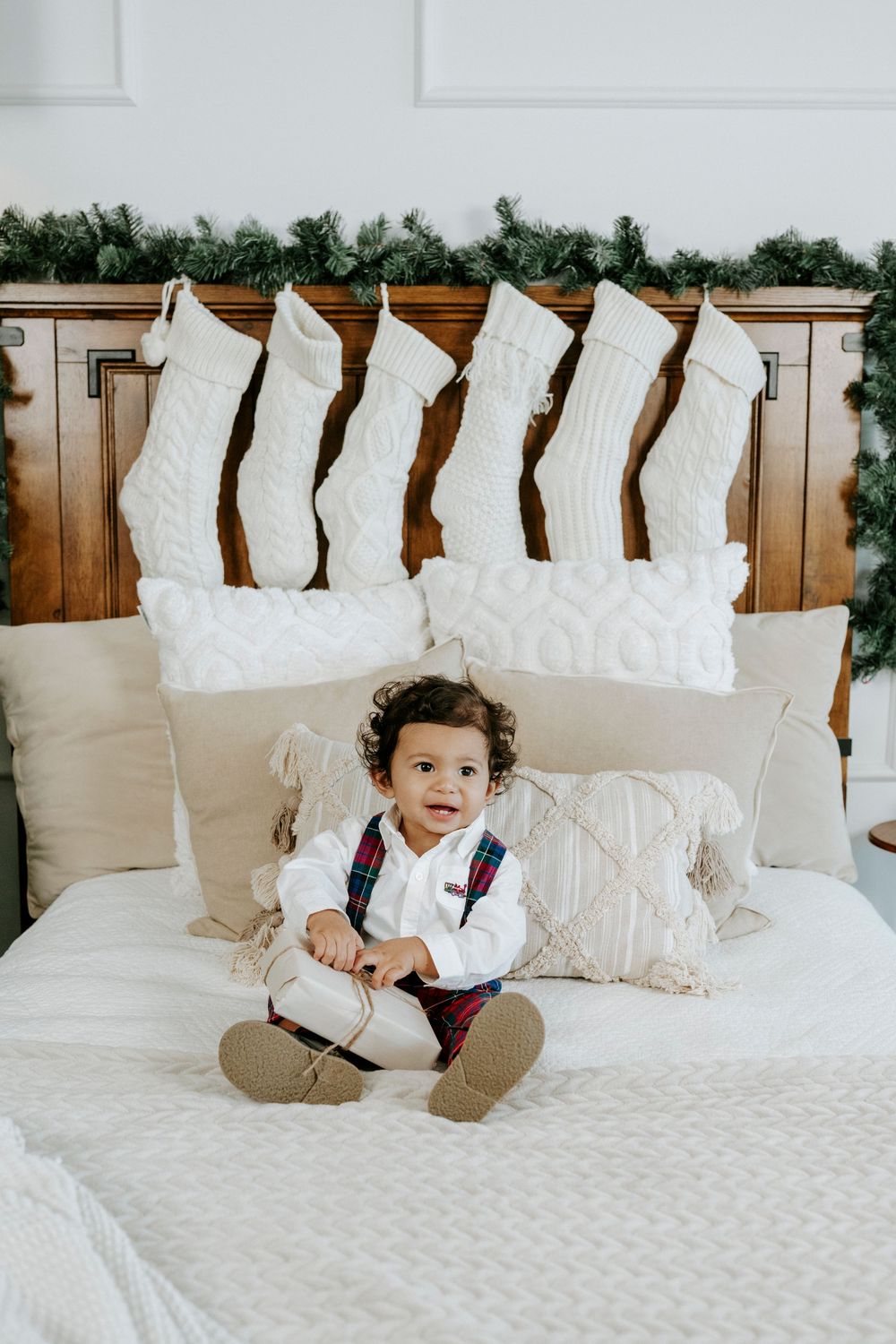 White throw pillows arranged in a row on a bed with a quilted white comforter and wooden headboard.