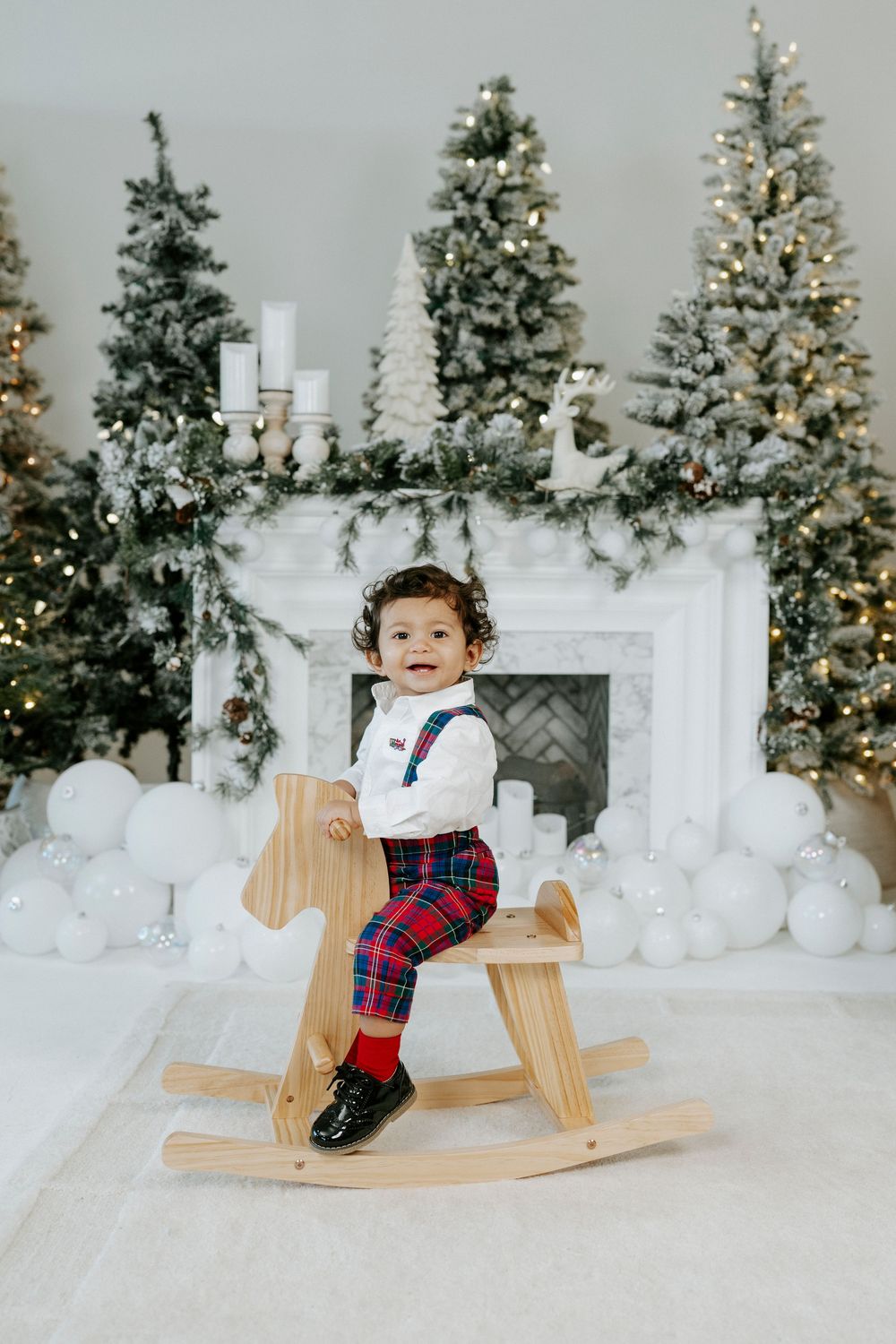 Rocking horse scene with Christmas trees and white fireplace decorated for winter holidays.