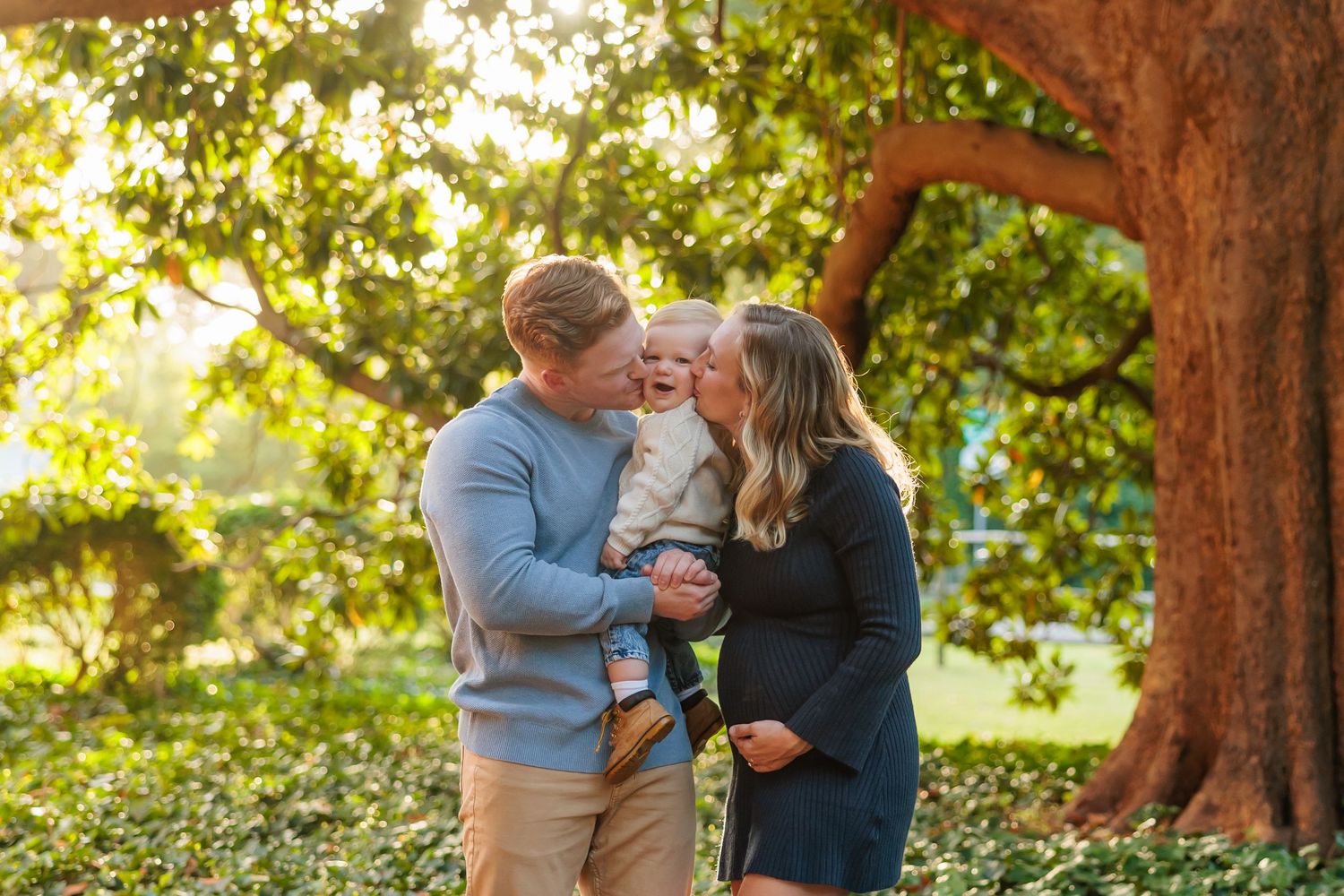 Family shares tender moment together outdoors in autumn garden with golden sunlight filtering through trees.