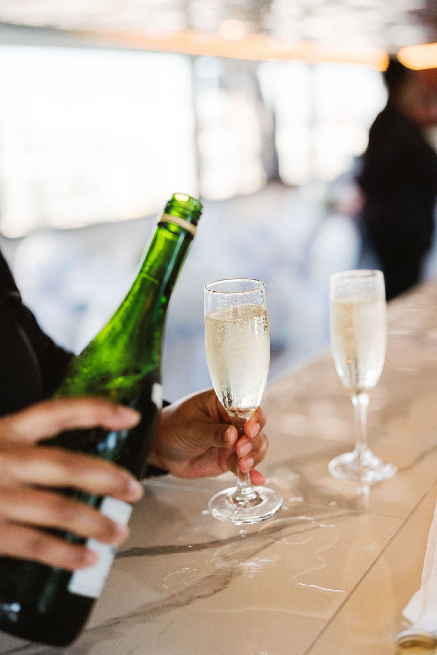 Champagne glasses and green bottles arranged on wooden table at celebration event.