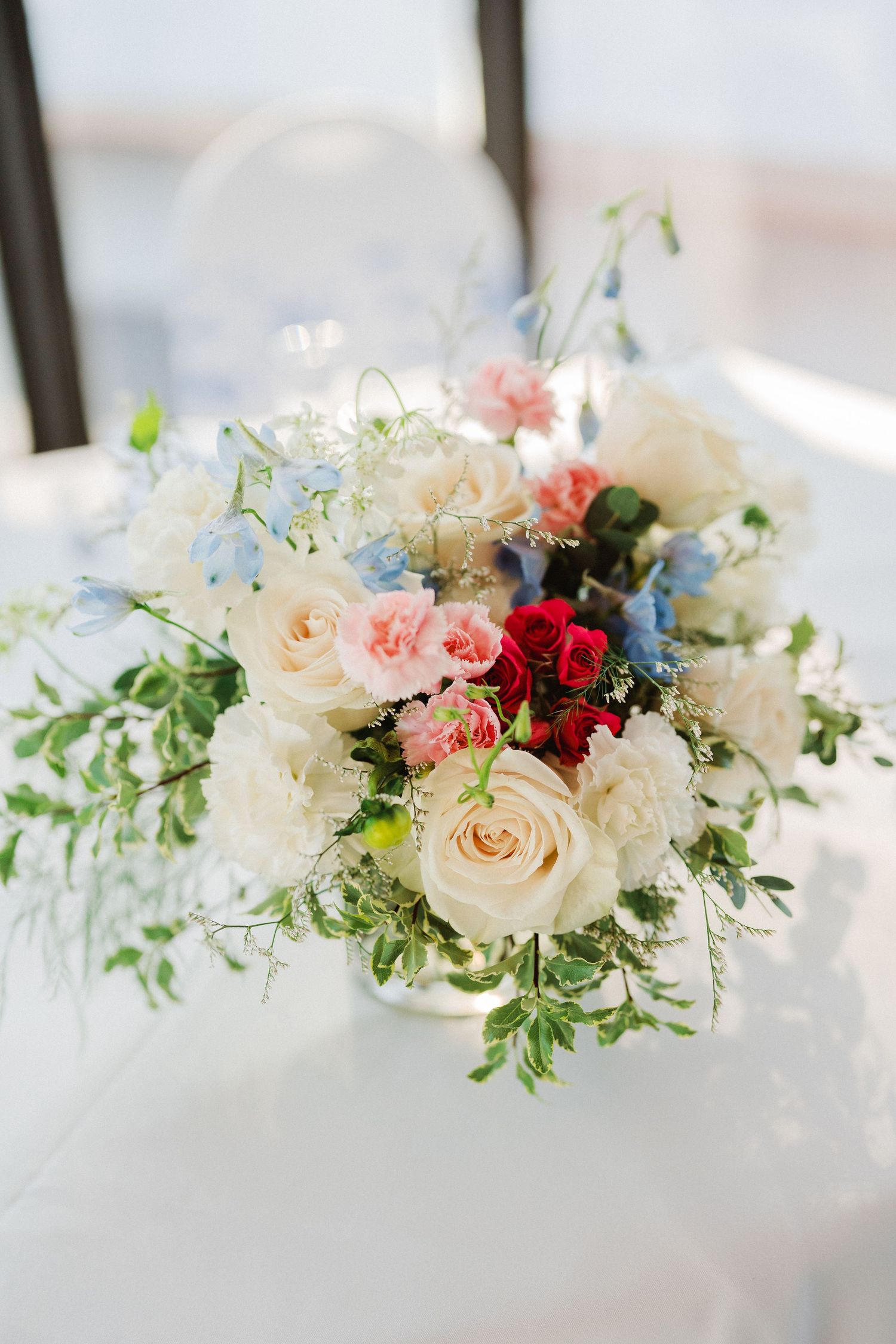 Elegant wedding centerpiece with blush roses, white flowers, and delicate greenery in a soft romantic arrangement.
