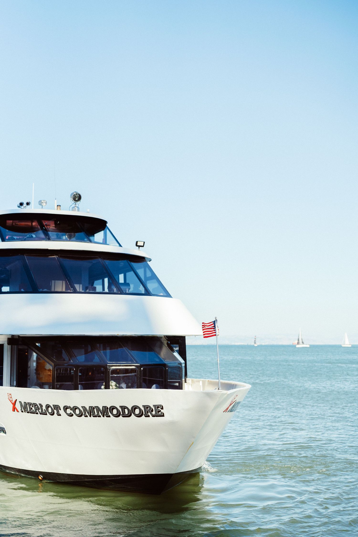 White yacht named Meloy Commodore sailing on blue waters under clear sky.