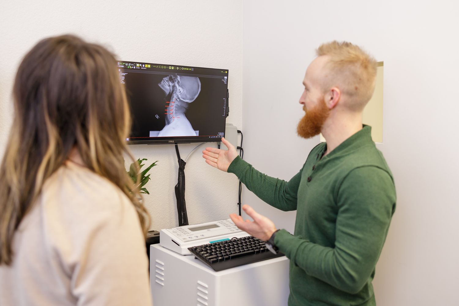 Limitless Chiropractor in Sumner, WA man pointing to xray chart while talking to female client in clinic for branding photo