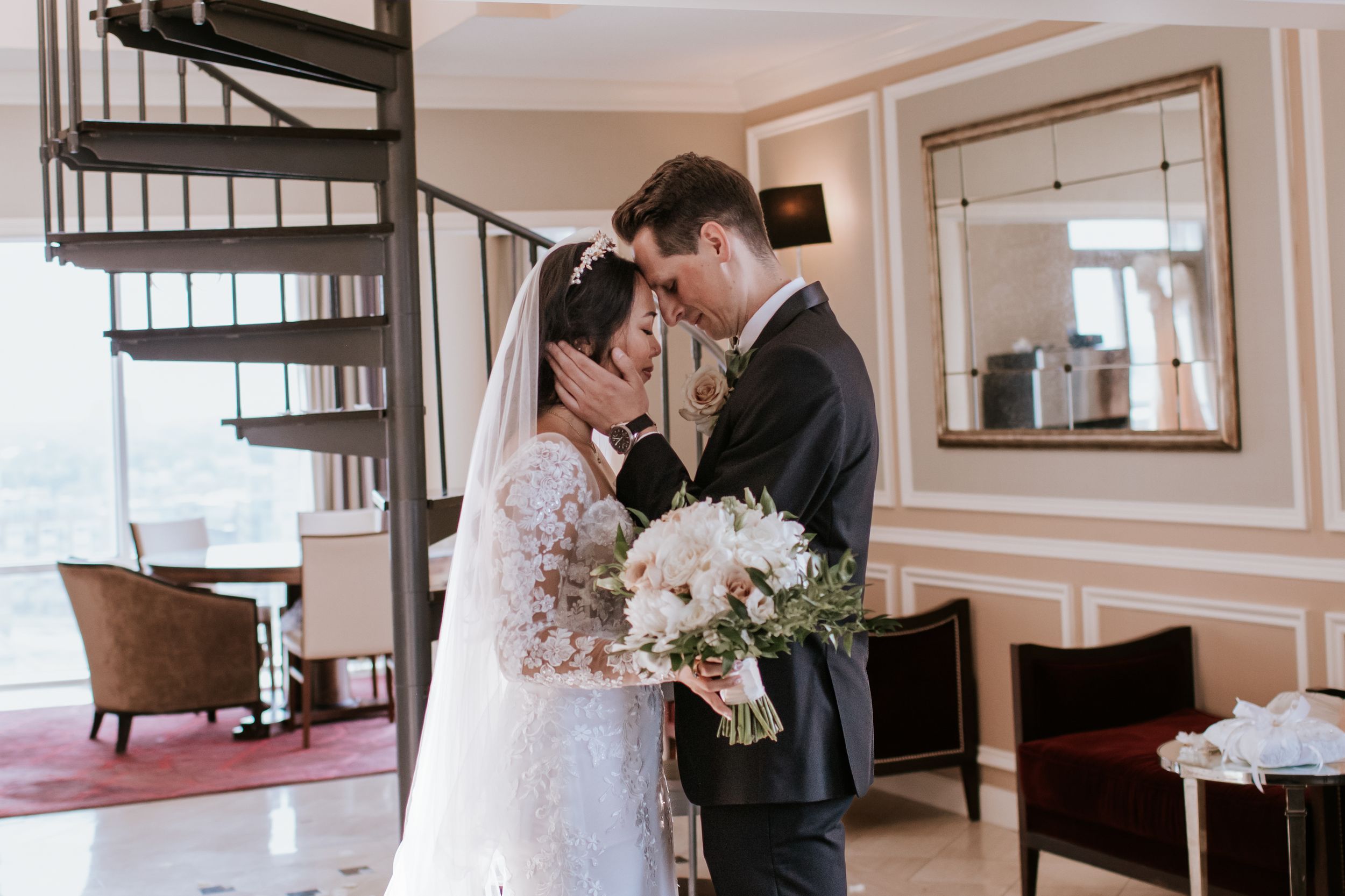Elegant wedding couple shares intimate moments in a luxurious indoor venue with soft lighting and floral arrangements.