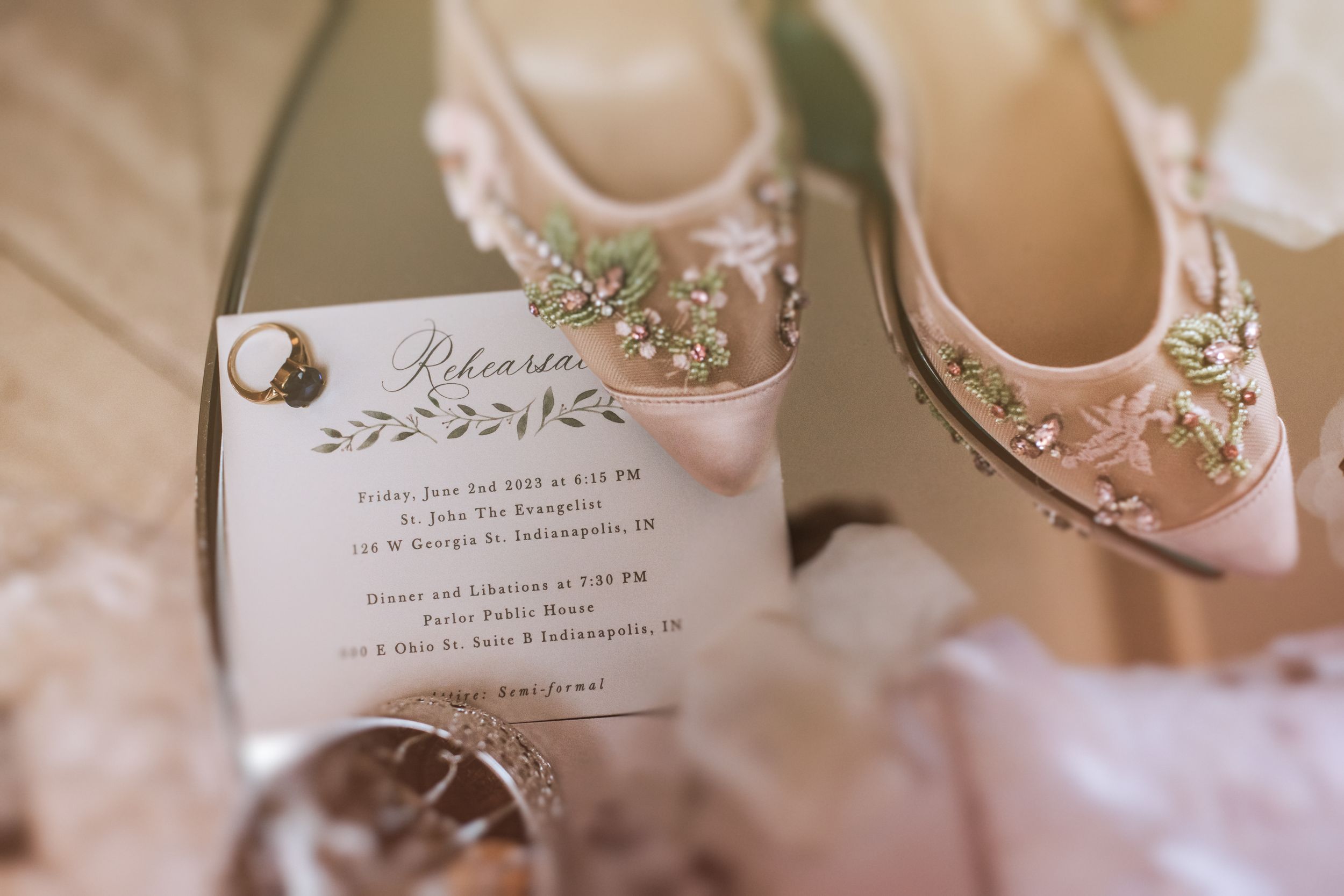 Elegant pink wedding shoes displayed with floral invitations and delicate jewelry on a soft textured background.
