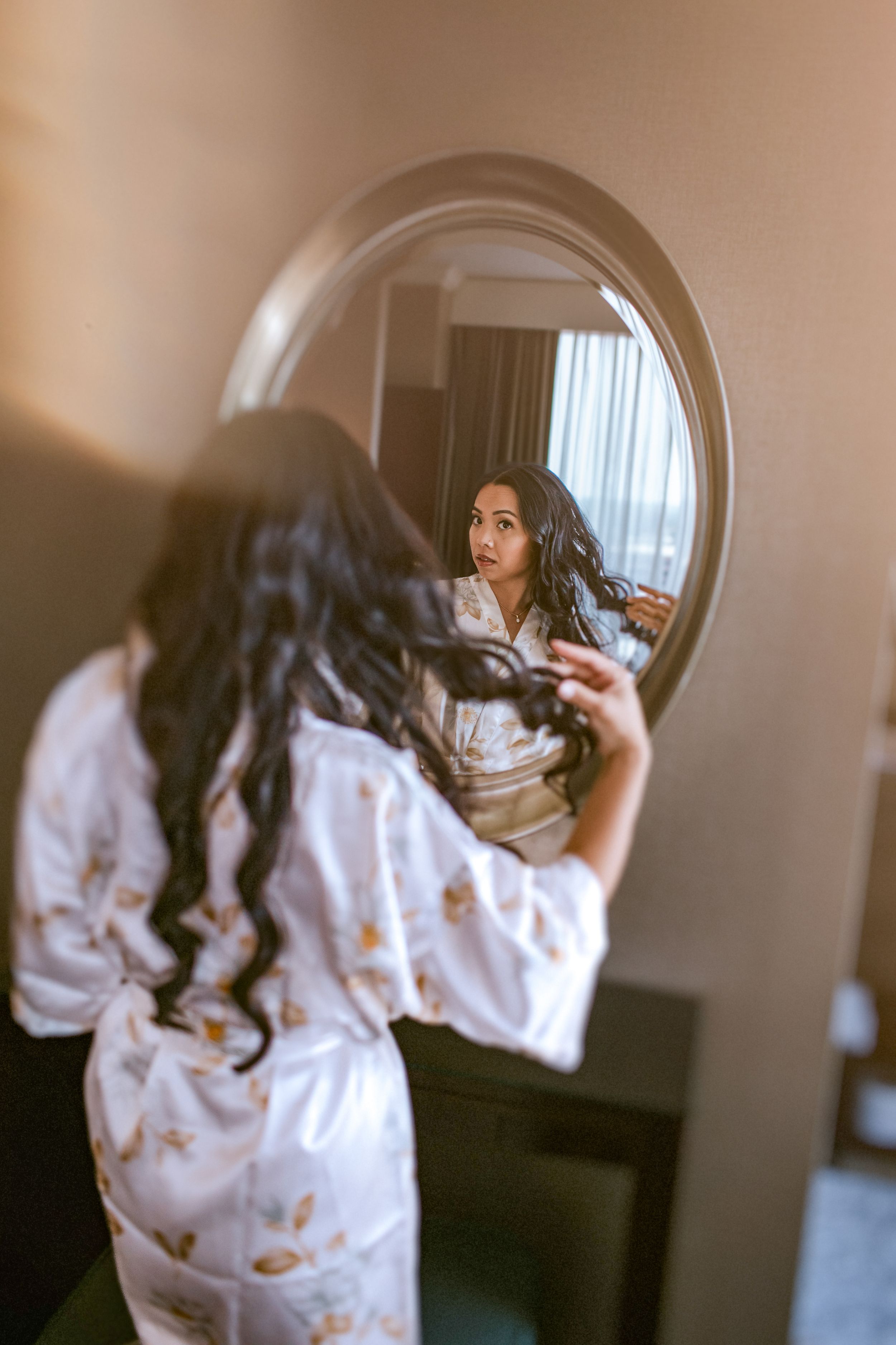A person wearing a white butterfly print sweater poses in front of a circular mirror in a dimly lit room.