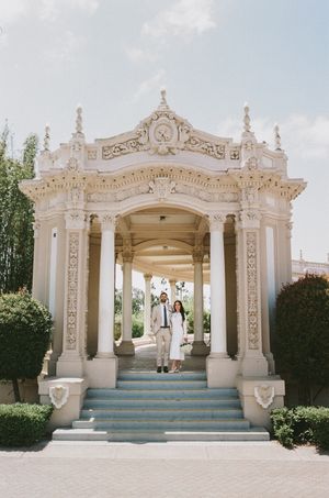 Elegant white architectural pavilion with ornate details and blue steps under bright sky.