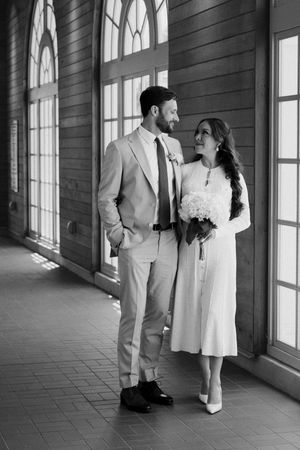 Monochrome images of a couple in white attire walking through an elegant corridor.