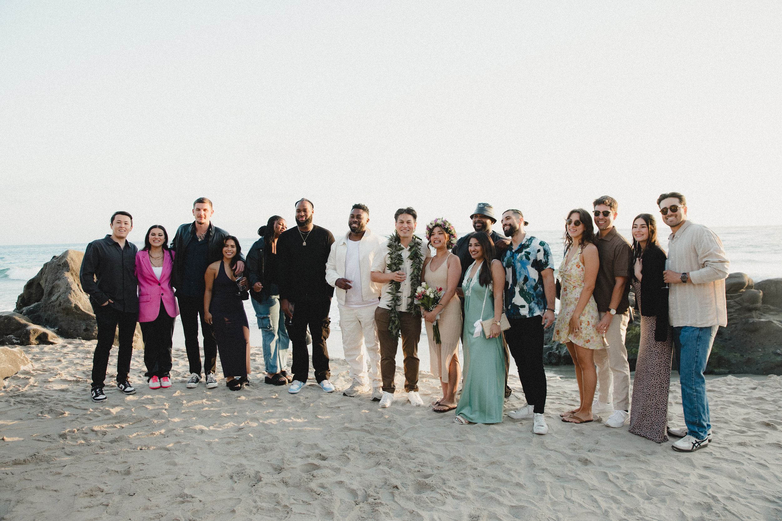 A group photo of wedding guests gathered on a scenic coastal overlook.