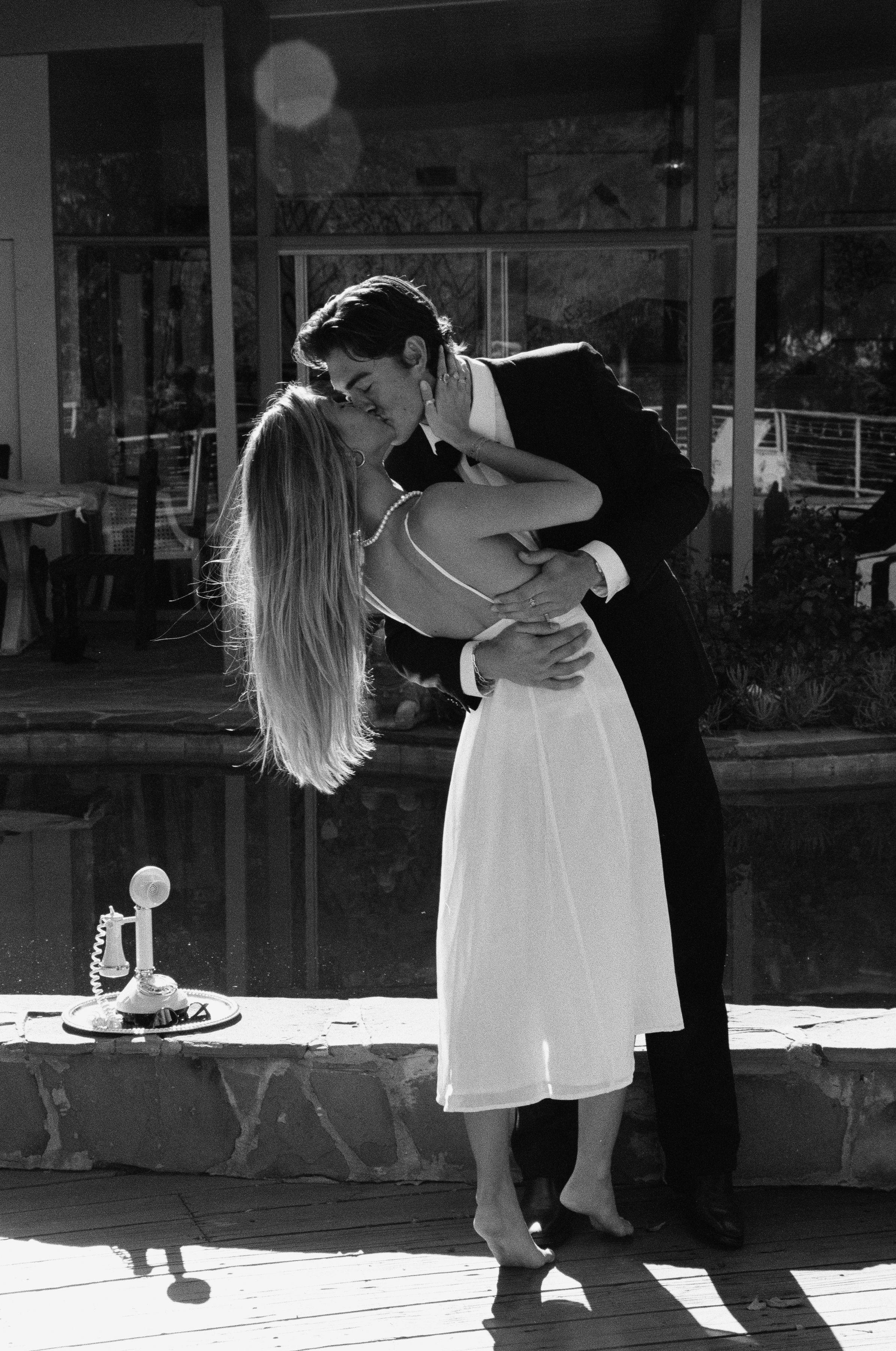 A romantic black and white photo of a couple sharing an intimate dance moment on a patio.