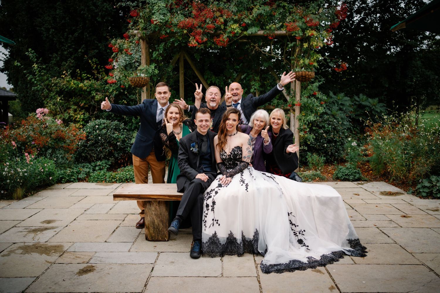Alternative Couple at clock barn wedding venue playing photo roulette together with their guests posing for a fun group photo