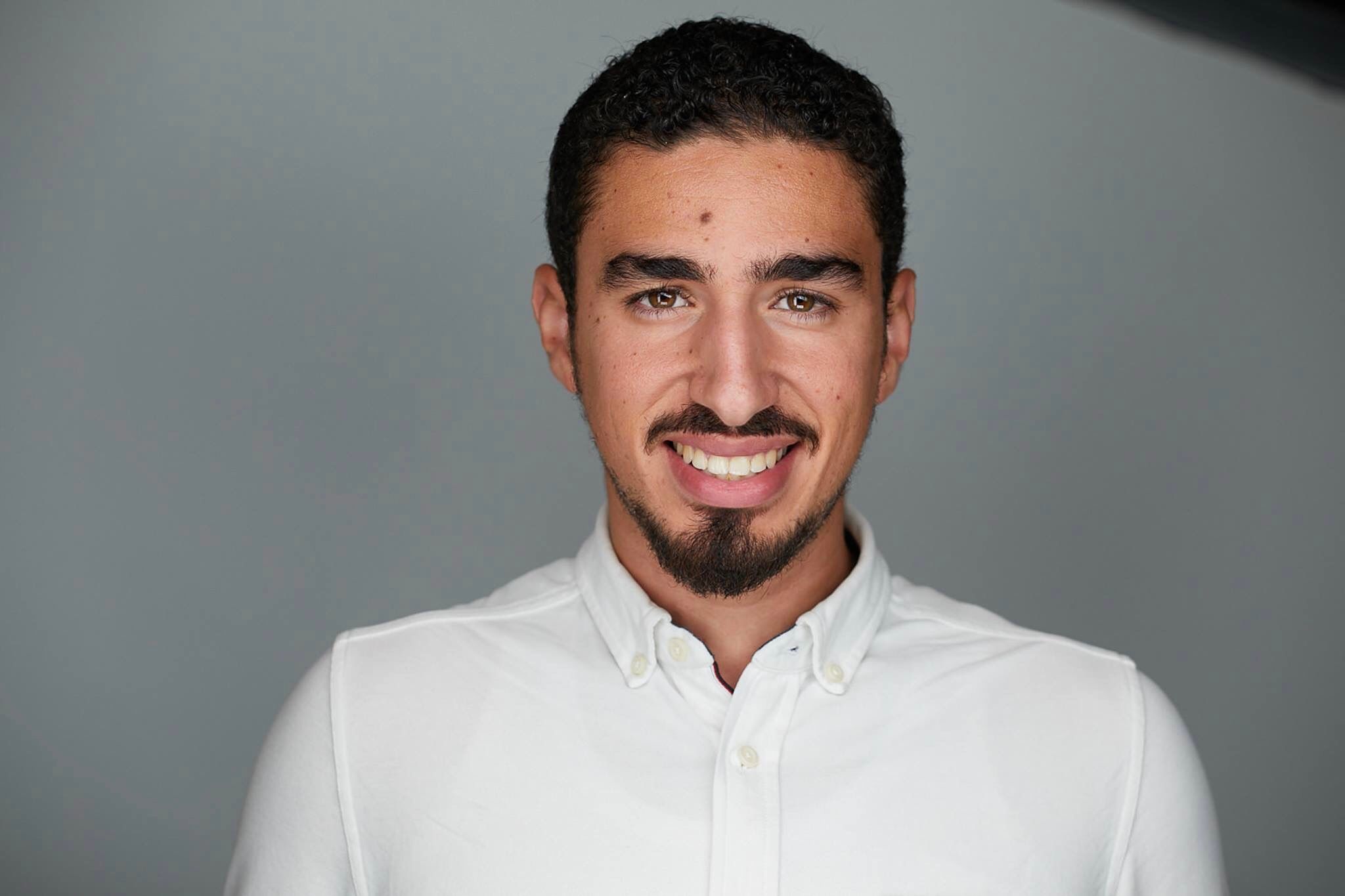 Young man with goatee smiling in professional white shirt portrait photo.