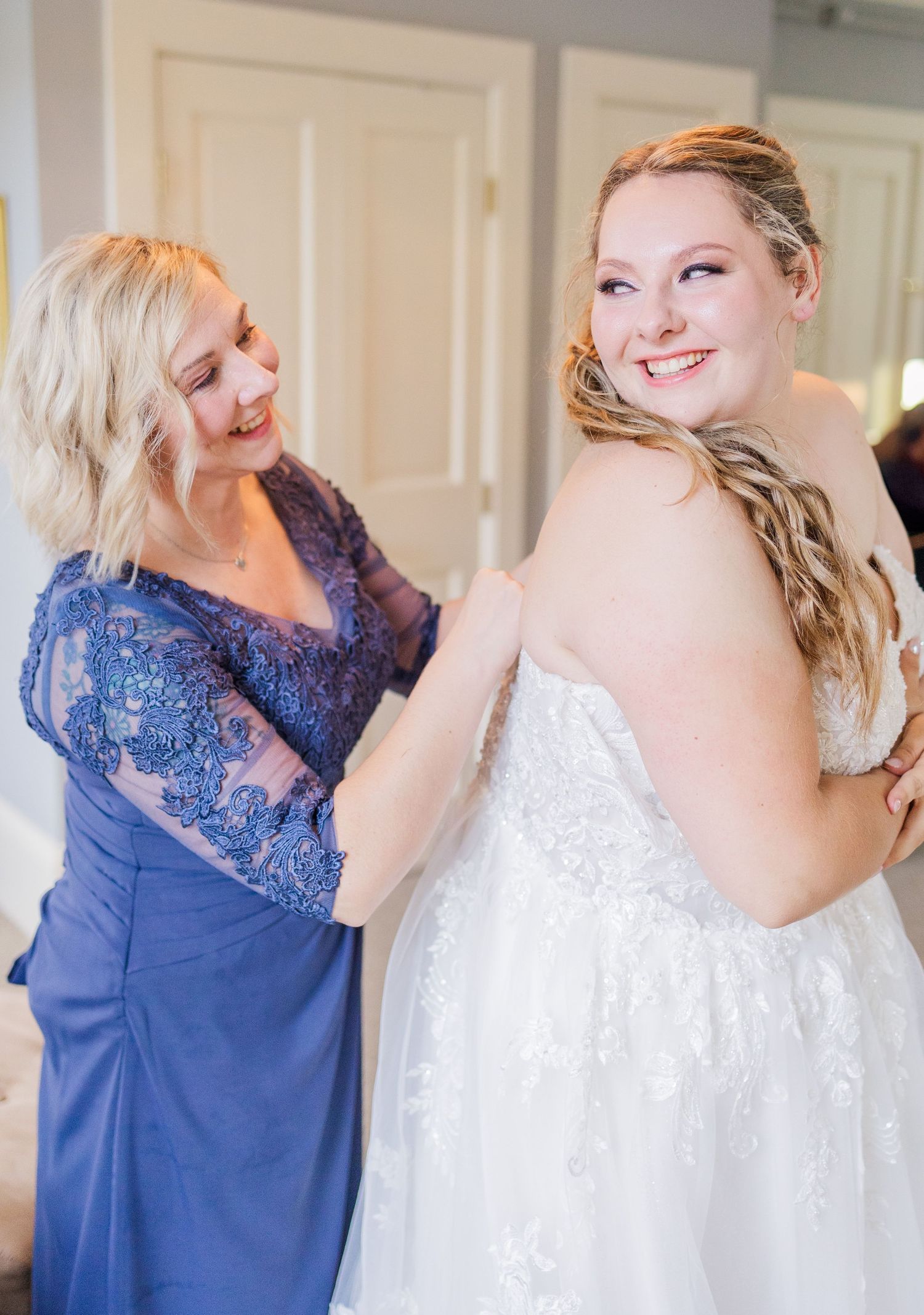 Wedding dress preparation moment with blue lace and white gown details.