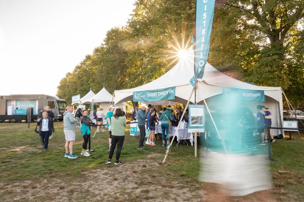 Outdoor festival setup with white tents and vendor booths arranged along a grassy area during golden hour.