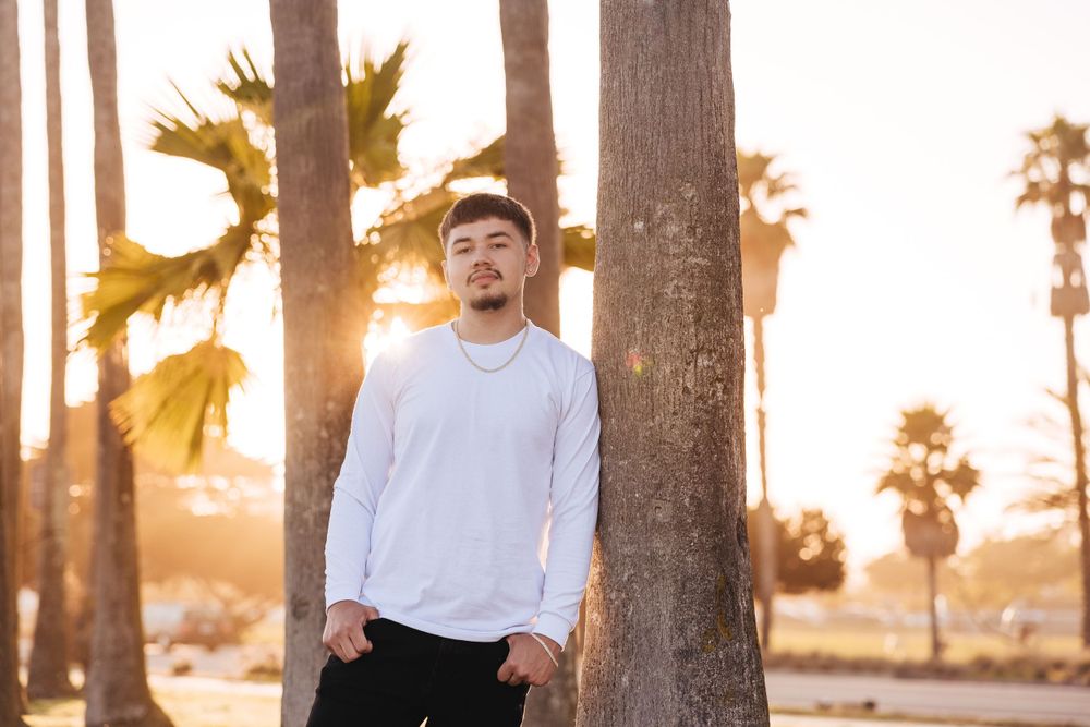 Candid moment captured between palm trees with warm sunset lighting.