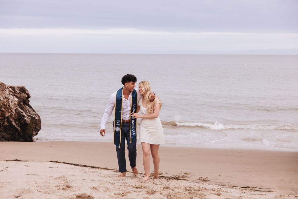 Couple walking together along sandy beach shoreline.