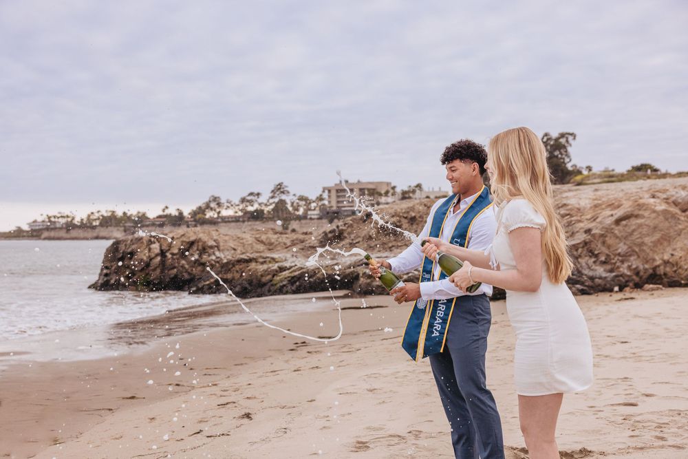 Couple walking hand in hand along scenic coastal beach during photo session.