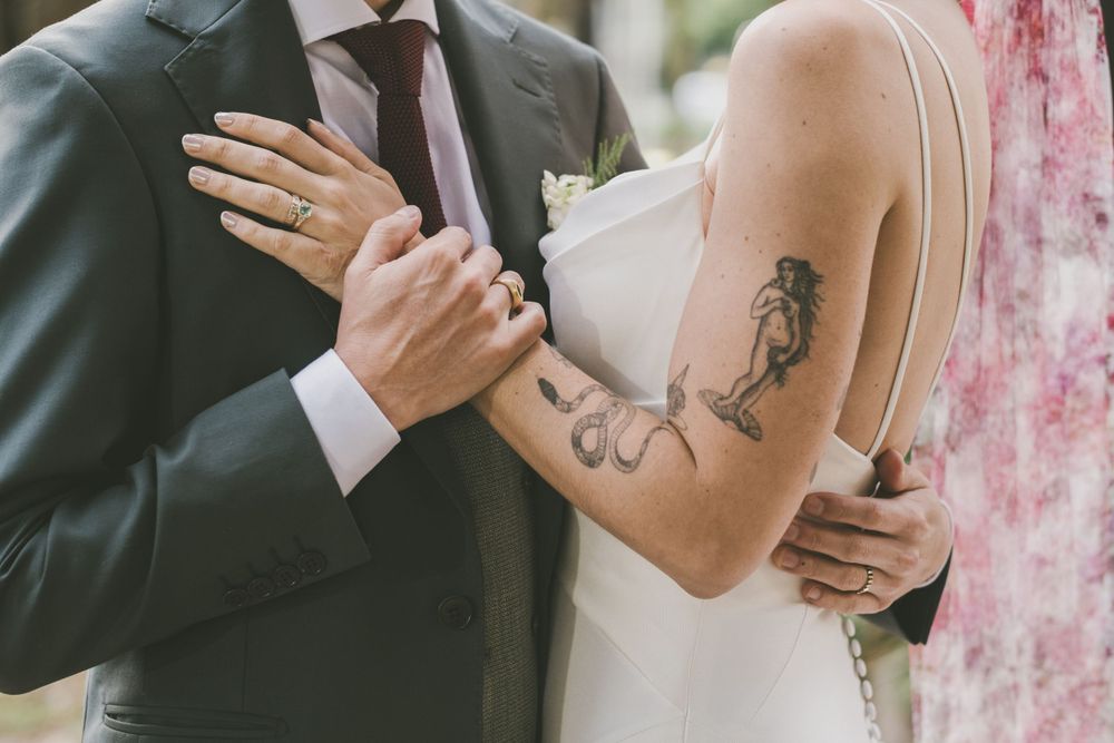 Bride with tattoos hugging her husband.
