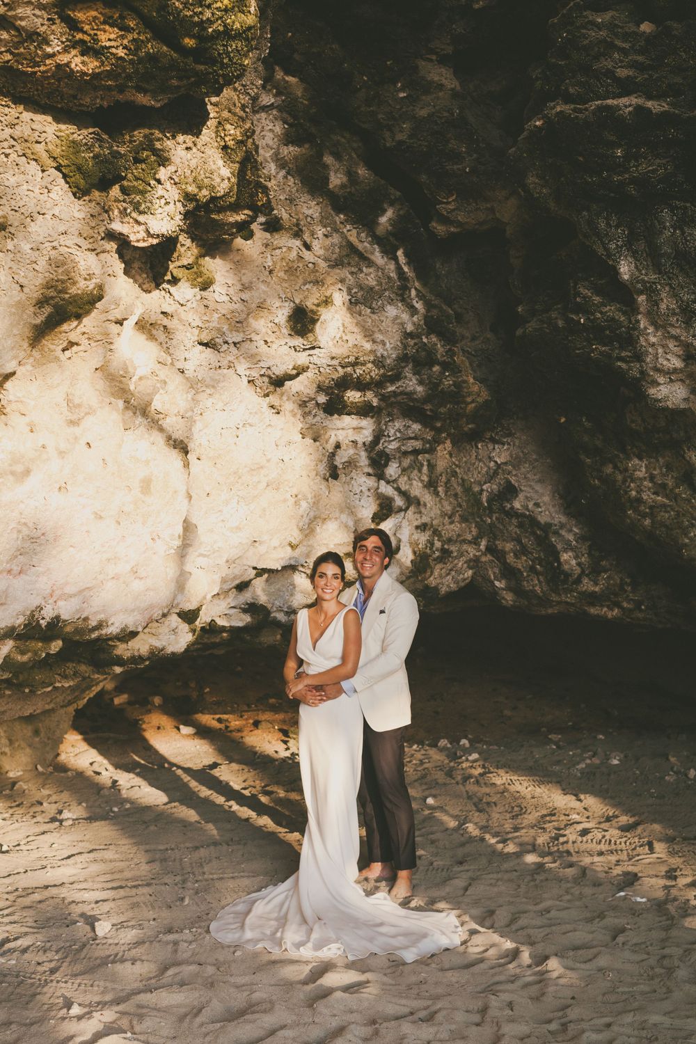 Newlyweds stand inside a cave by the beach in Colombia.