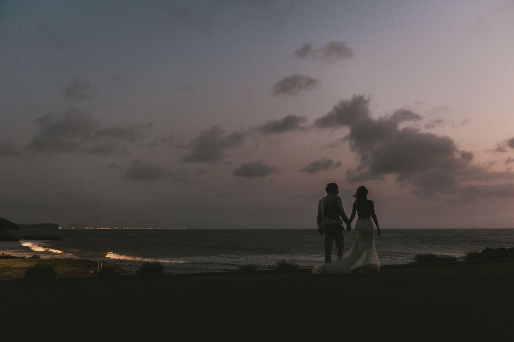 Newlyweds walking on a Colombian beach at sunset.