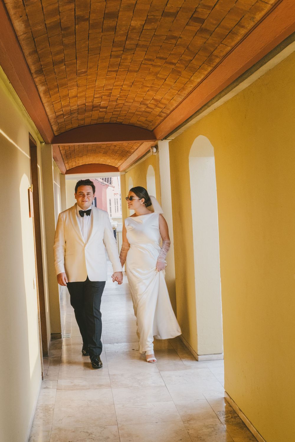Newlyweds walking inside a colonial hallway in Cartagena.