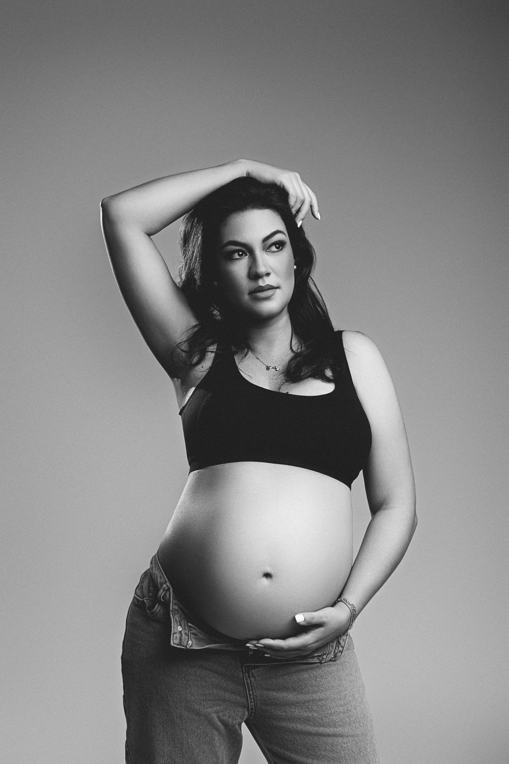 Black and white maternity portrait with dramatic pose and natural lighting.