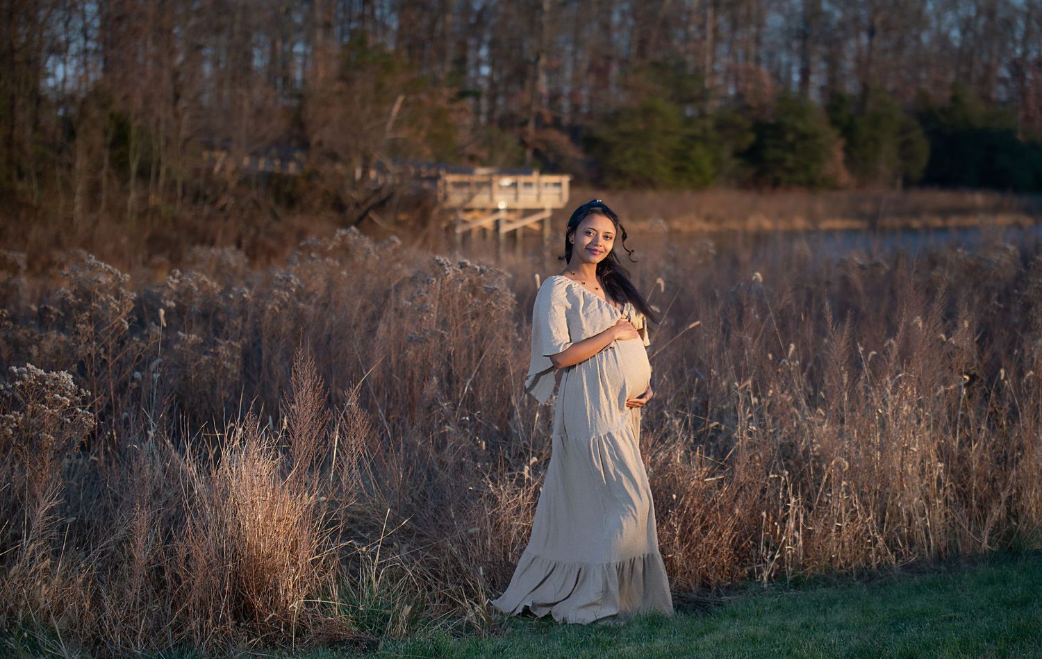 Maternity photography session in natural setting with dramatic evening light and winter foliage.