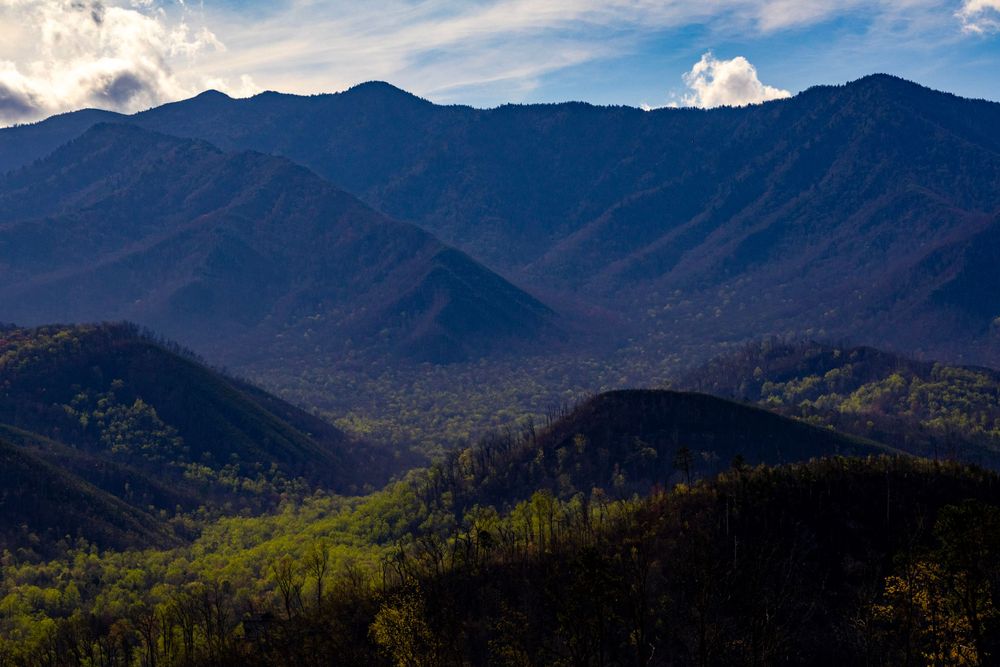 Morning light illuminates a scenic mountain landscape in the Great Smoky Mountains with layered ridges and forested slopes.