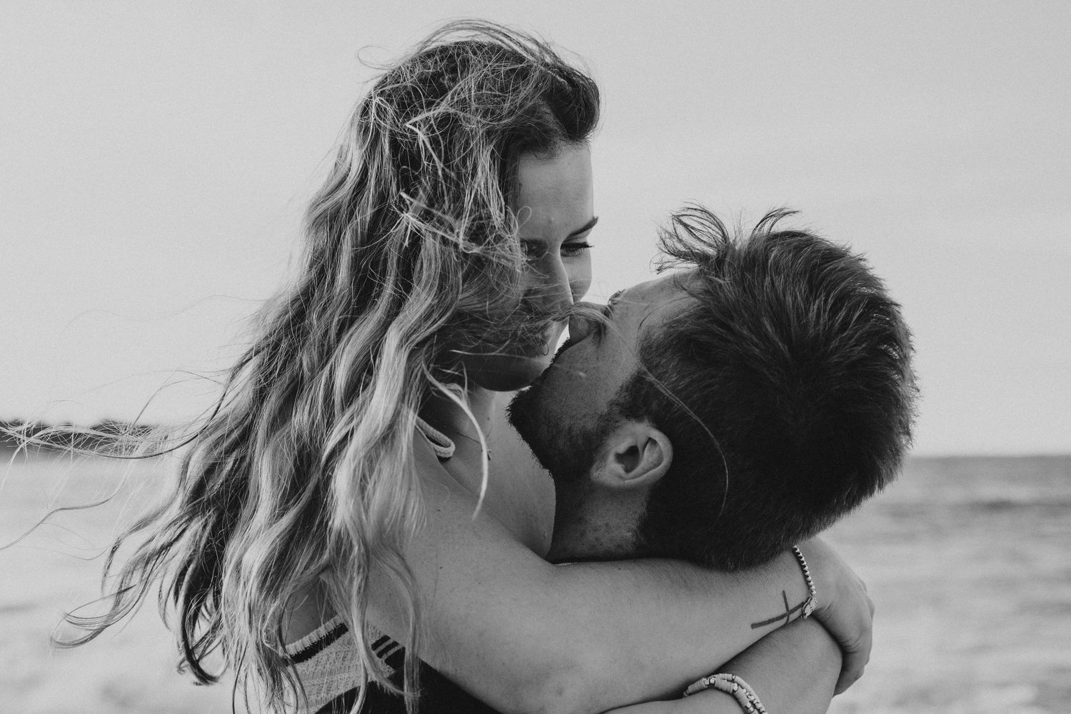 Black and white romantic photo of couple embracing on beach.