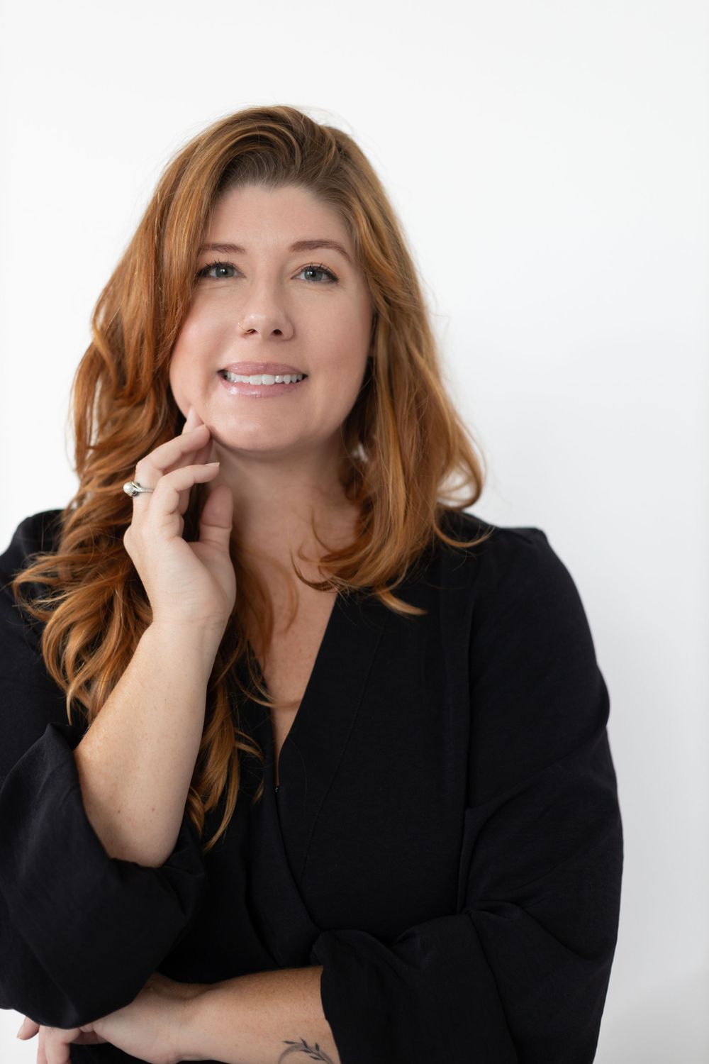 A professional headshot against a white background featuring warm lighting.