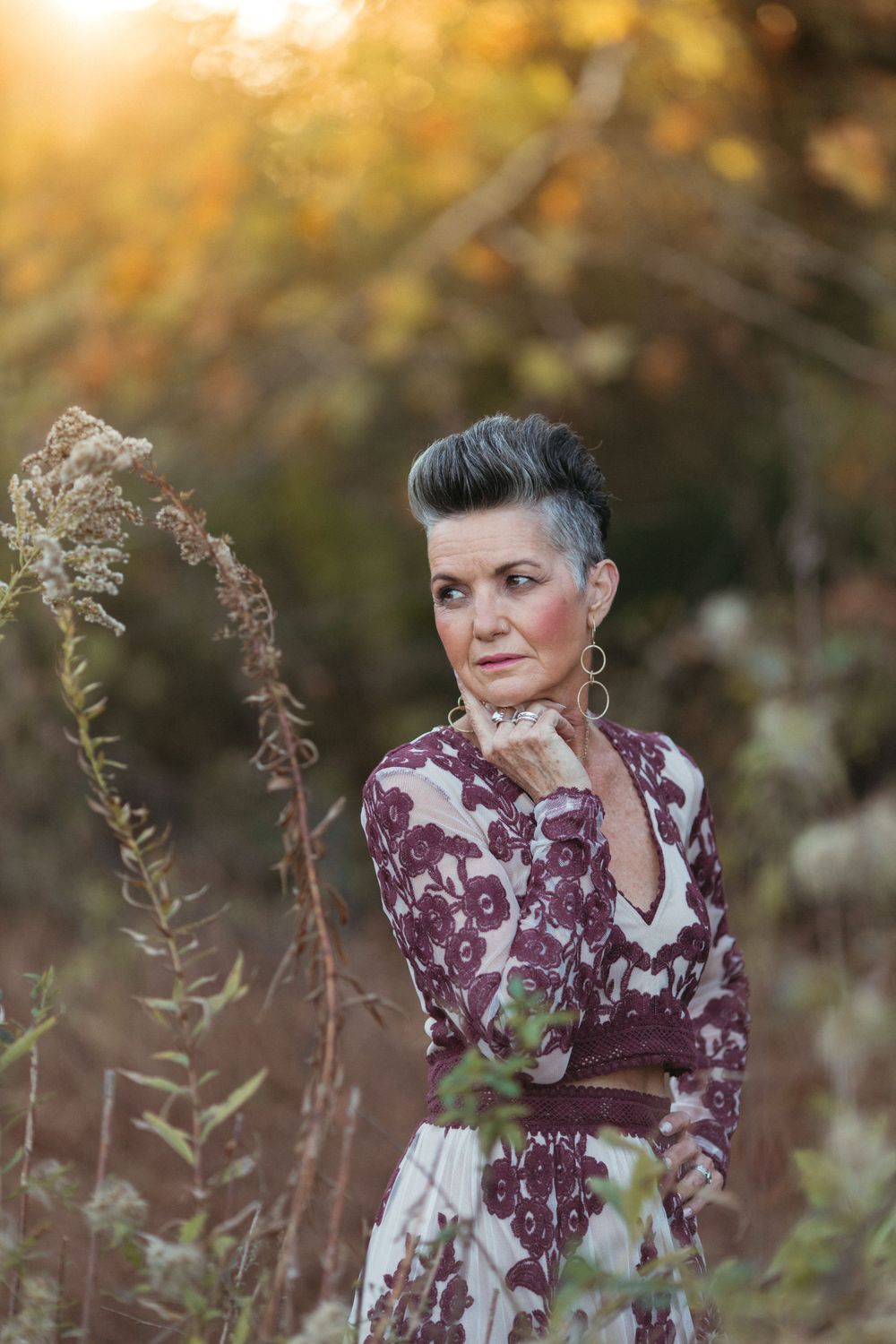 Beautiful burgundy dress with fall foliage and golden sunlight in outdoor portrait setting.
