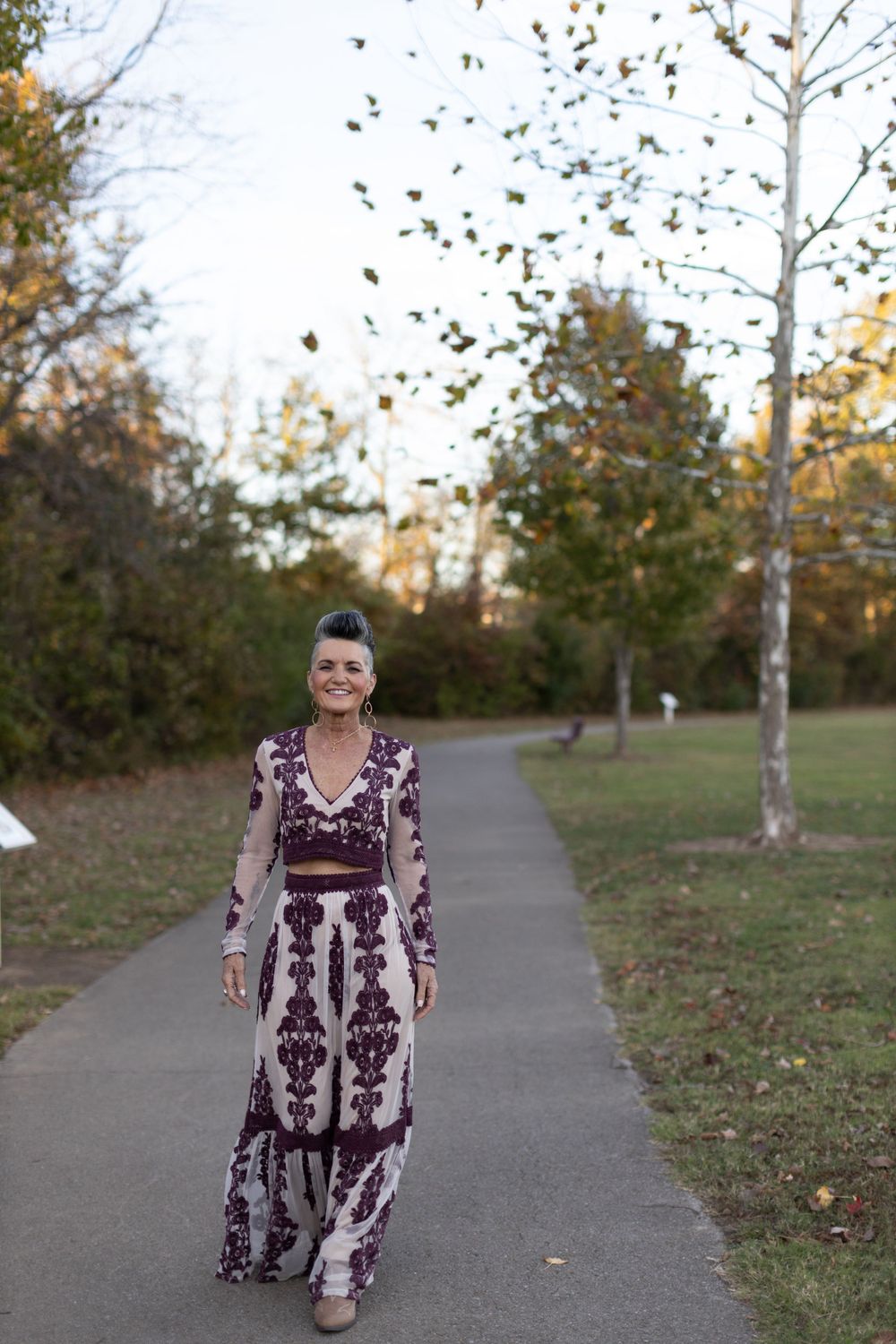 Stylish dress worn while walking on path with falling autumn leaves overhead.