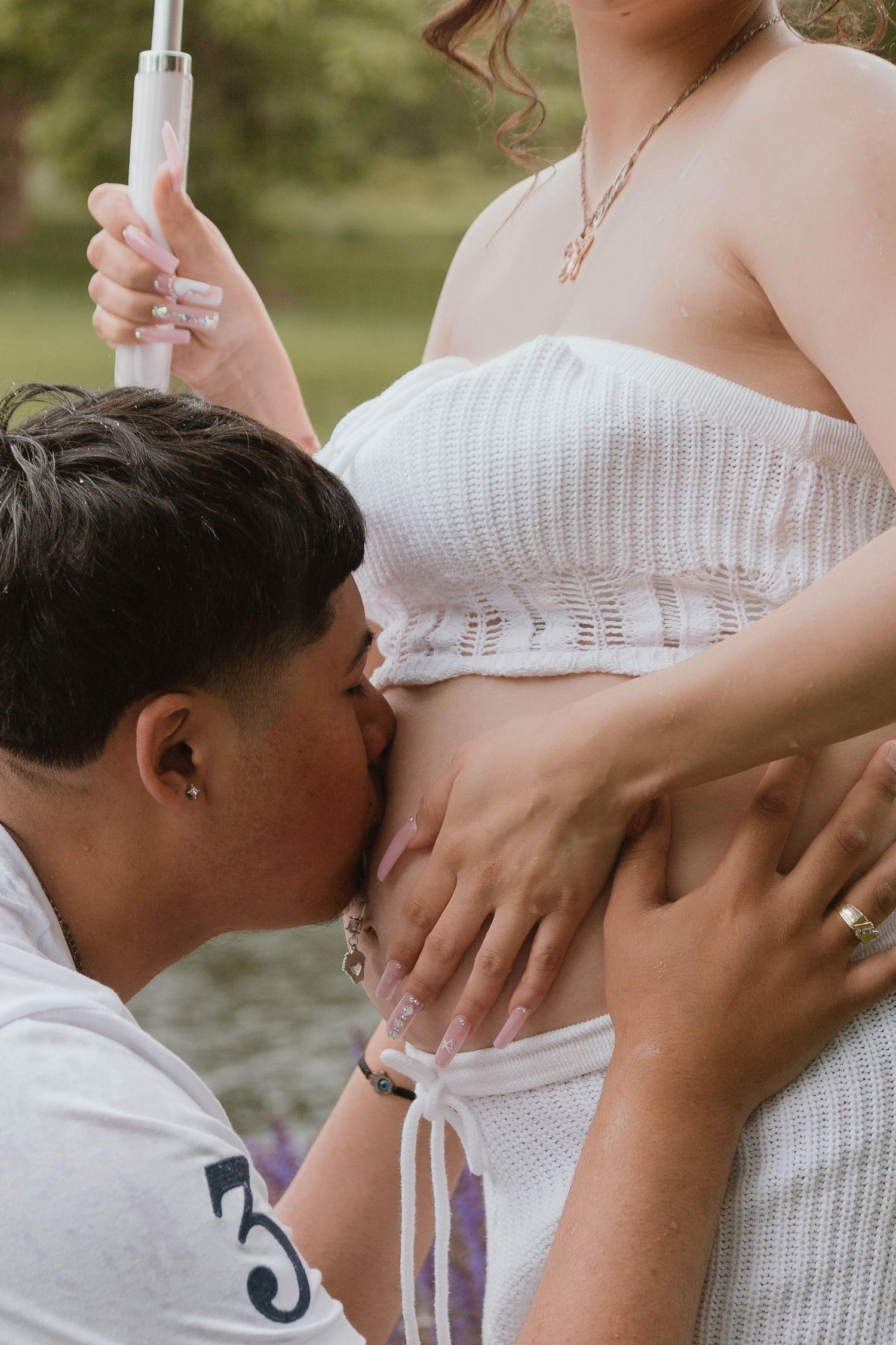 A tender pregnancy photo showing a close embrace and positive pregnancy test against a soft outdoor background.