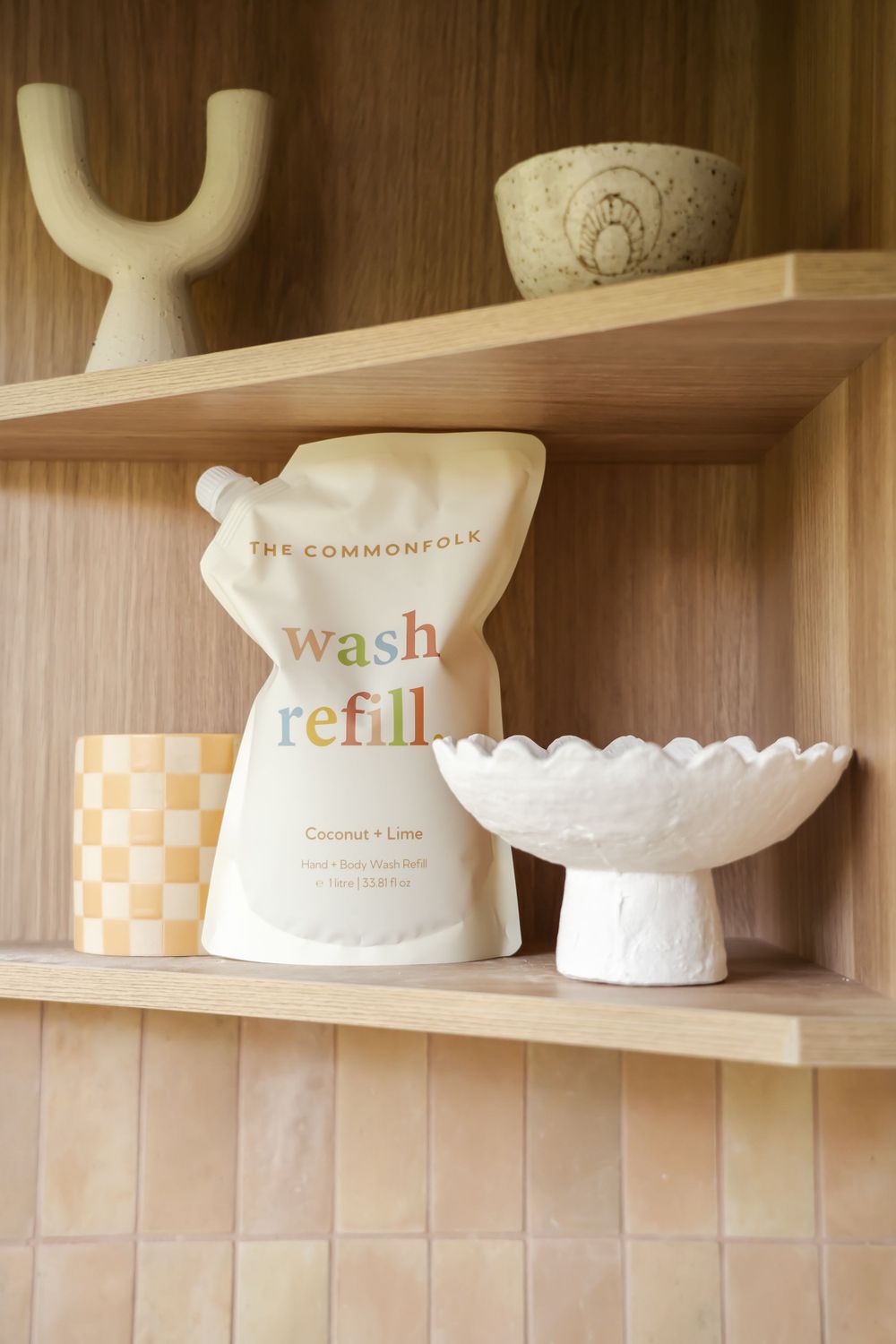 Bathroom shelf displaying decorative ceramic pieces and a washable refill pouch in natural tones.