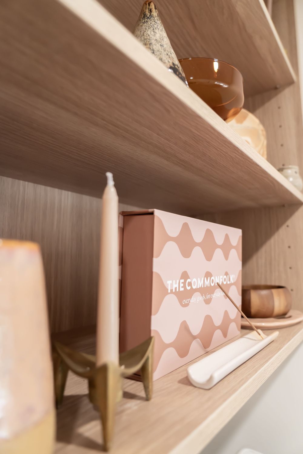 Wooden shelving unit with sustainable home products and decorative items in neutral colors.