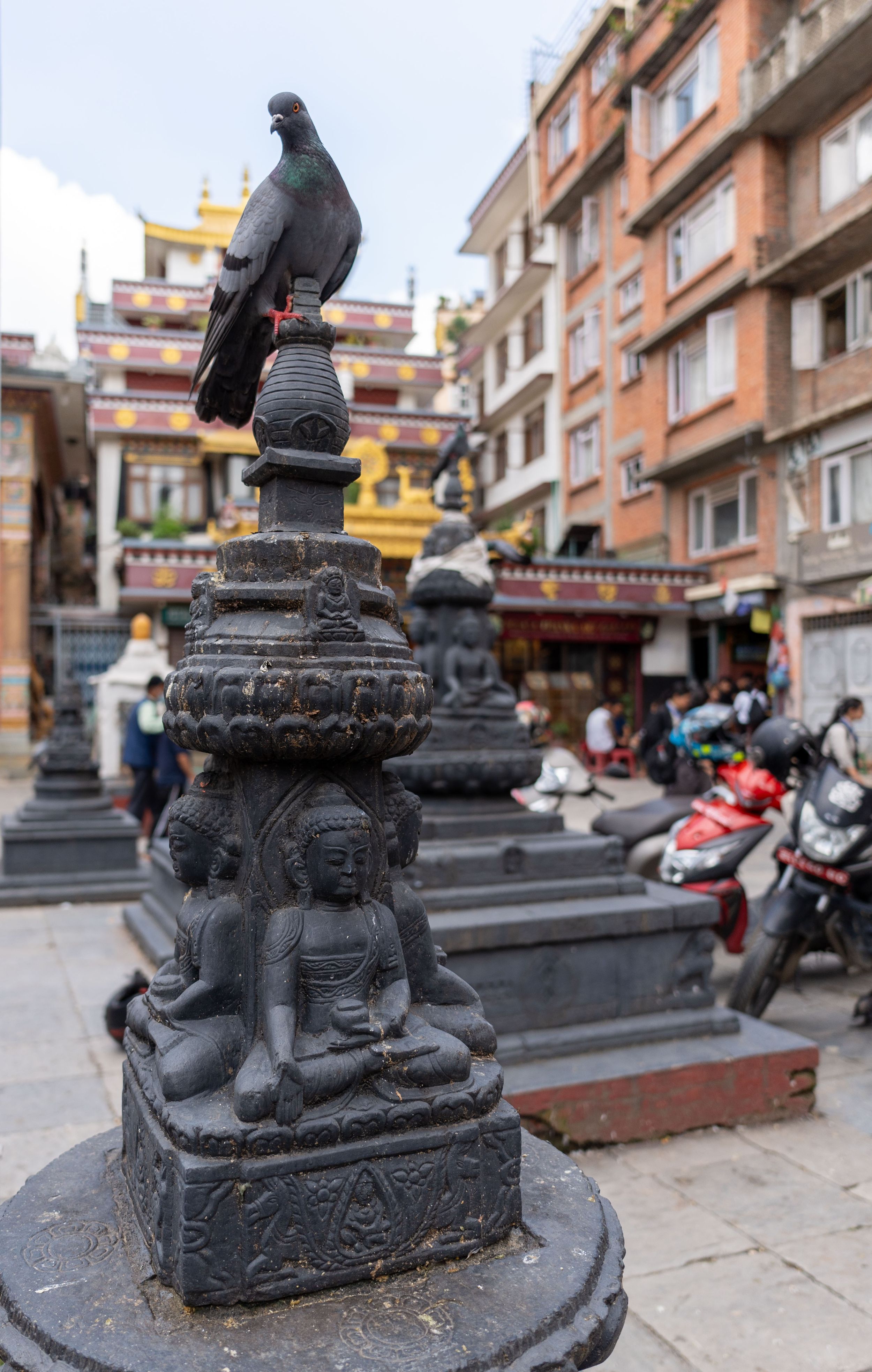 Stone sculptures and religious monuments along a street in a Tibetan neighborhood.