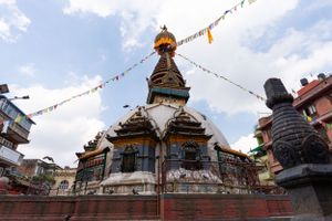 Buddhist stupa with colorful prayer flags against cloudy sky in Nepal.
