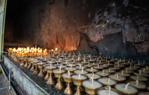Rows of traditional butter lamps illuminating a dark temple interior.