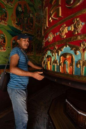 Ornate Buddhist prayer wheels with decorative red and gold patterns inside temple.