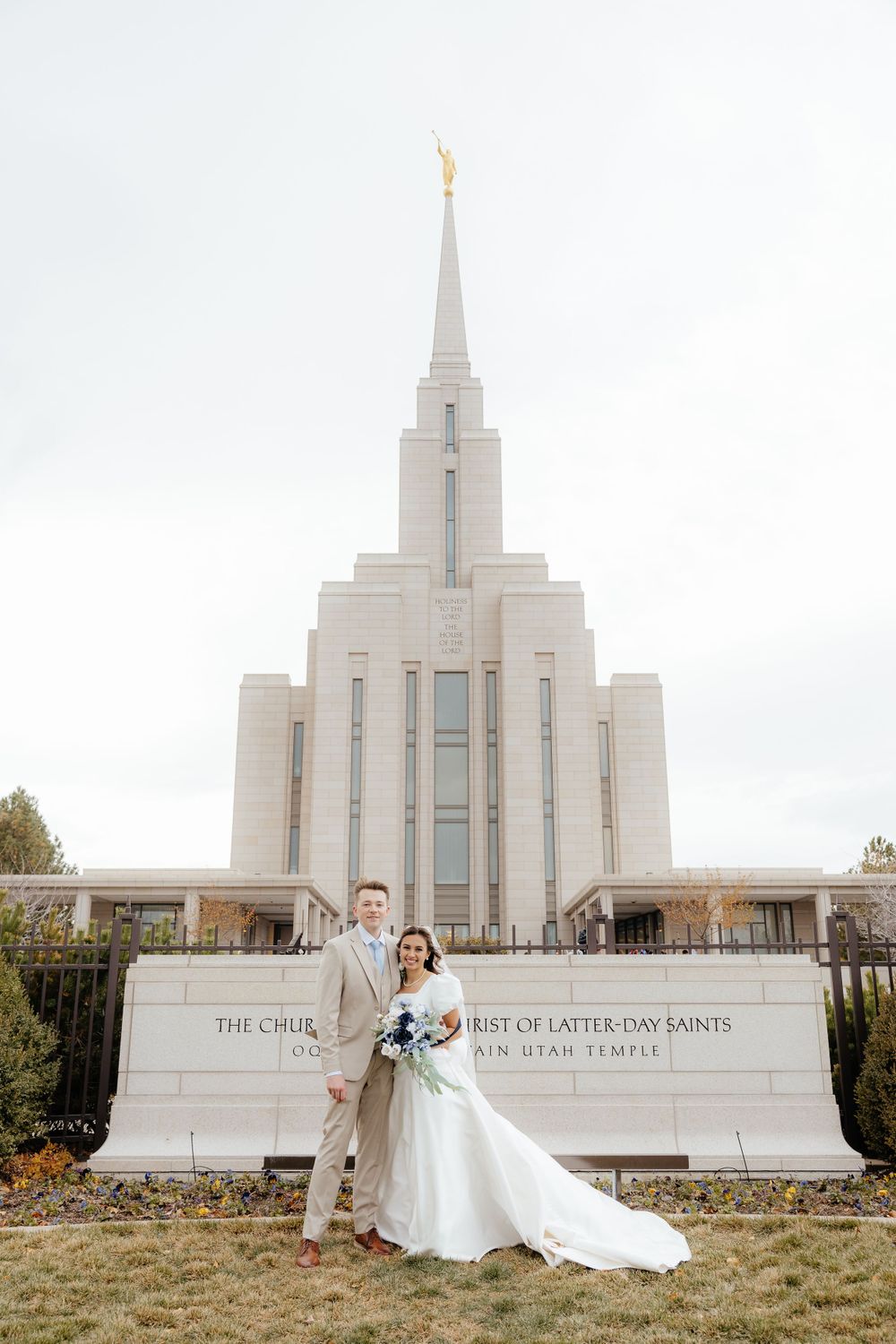 Bride and groom posing in front of the Oquirrh Mountain Utah LDS Temple on their wedding day.